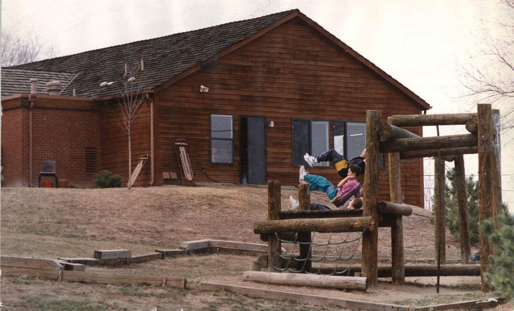 children swinging on playground structure in front of school